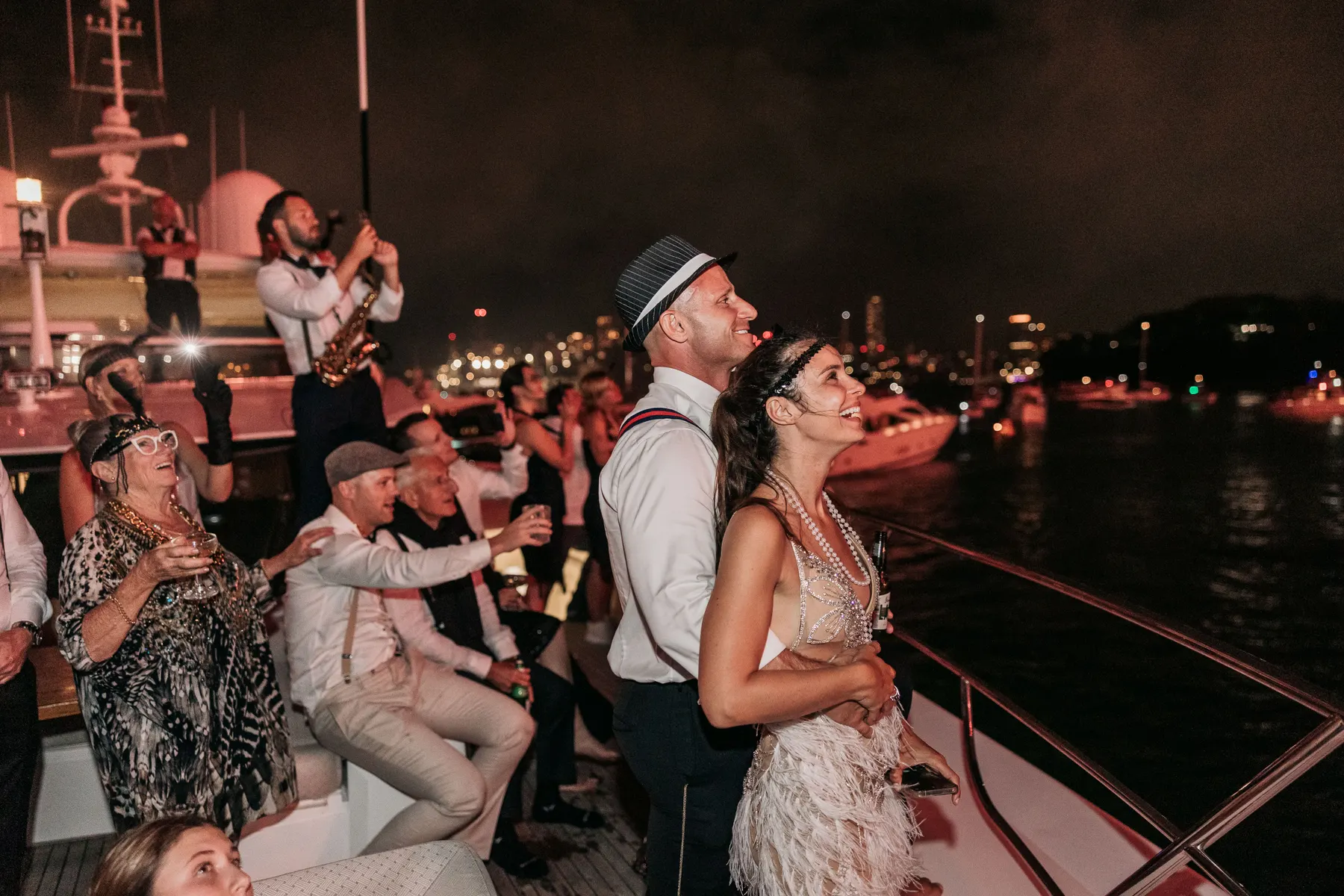 Guests on deck looking up at the fireworks while a saxophonist plays