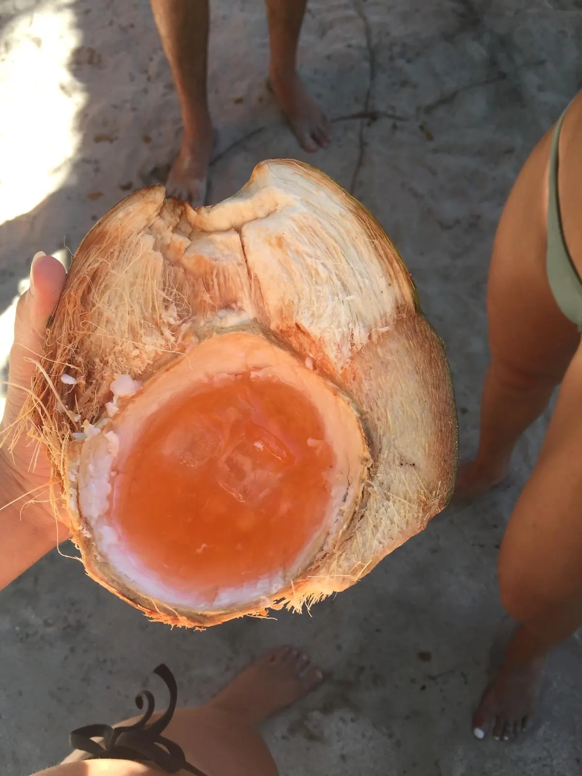 An Aperol spritz served in a fresh coconut on the beach
