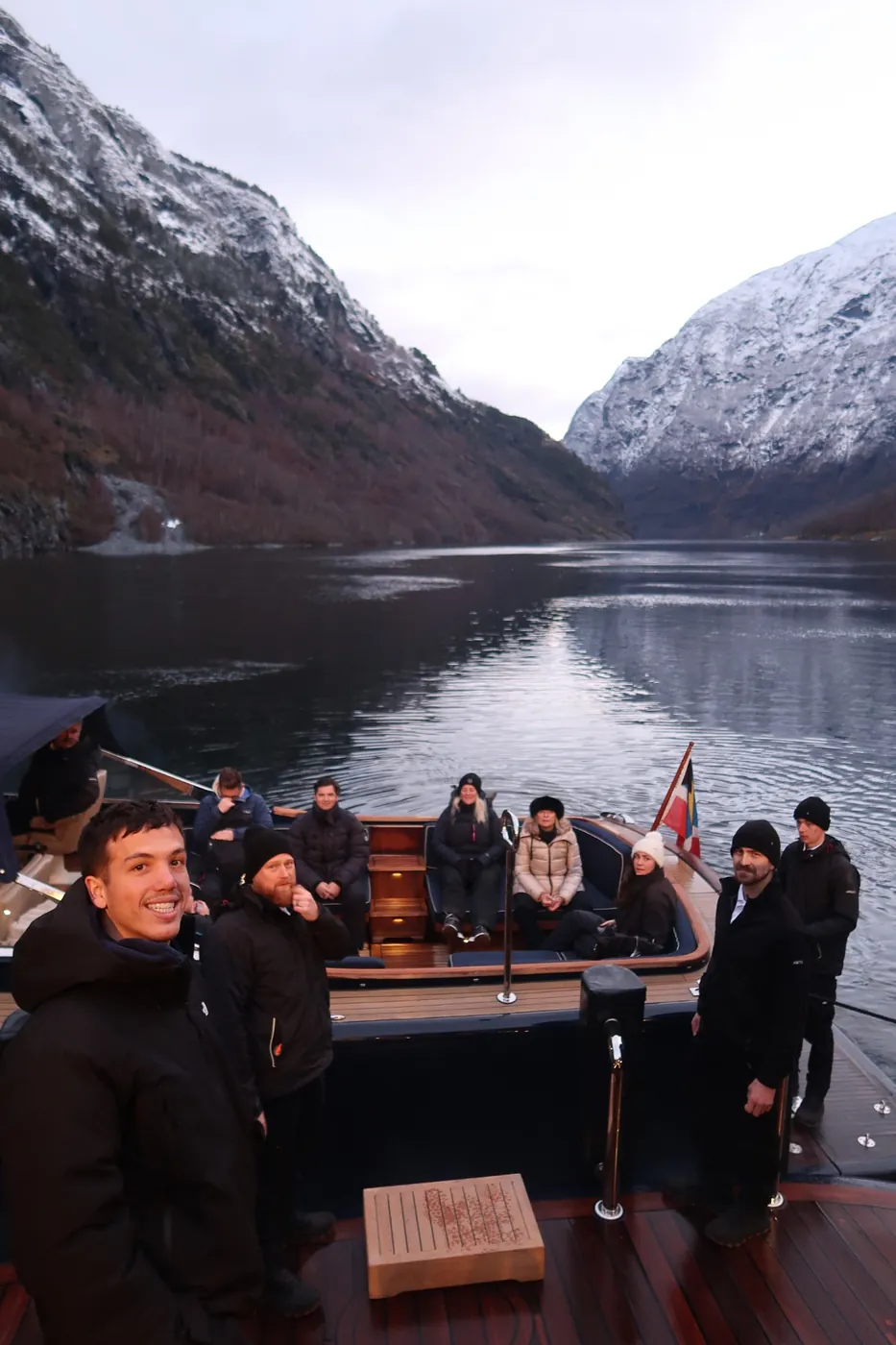 Guests settled in ARCTIC's Riva tender at the stern, crew alongside, snowy fjord walls behind