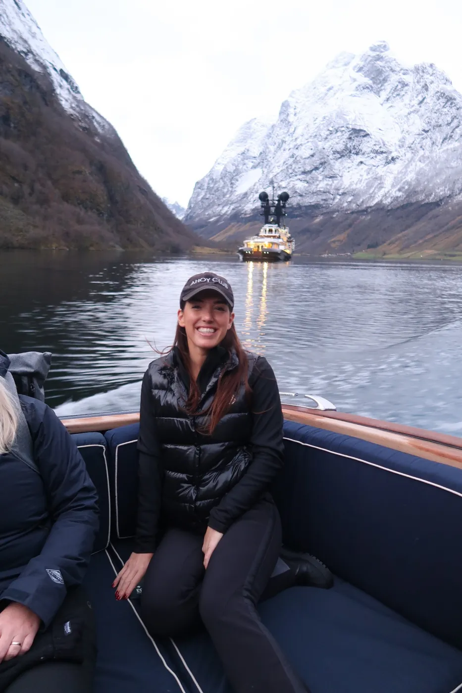 Ellie in one of ARCTIC's tenders on the fjord, ARCTIC lit up behind under snowy peaks