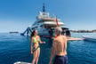 Couple paddleboarding next to mischief superyacht