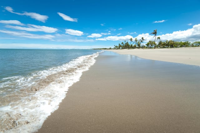 A wide white sandy beach to the blue sea under a blue sky