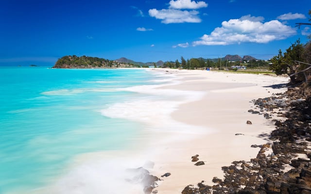White beach with crystal-clear waters under bright blue sky in Antigua